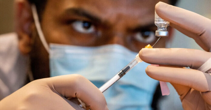 Covid Vaccine being drawn by a tech.