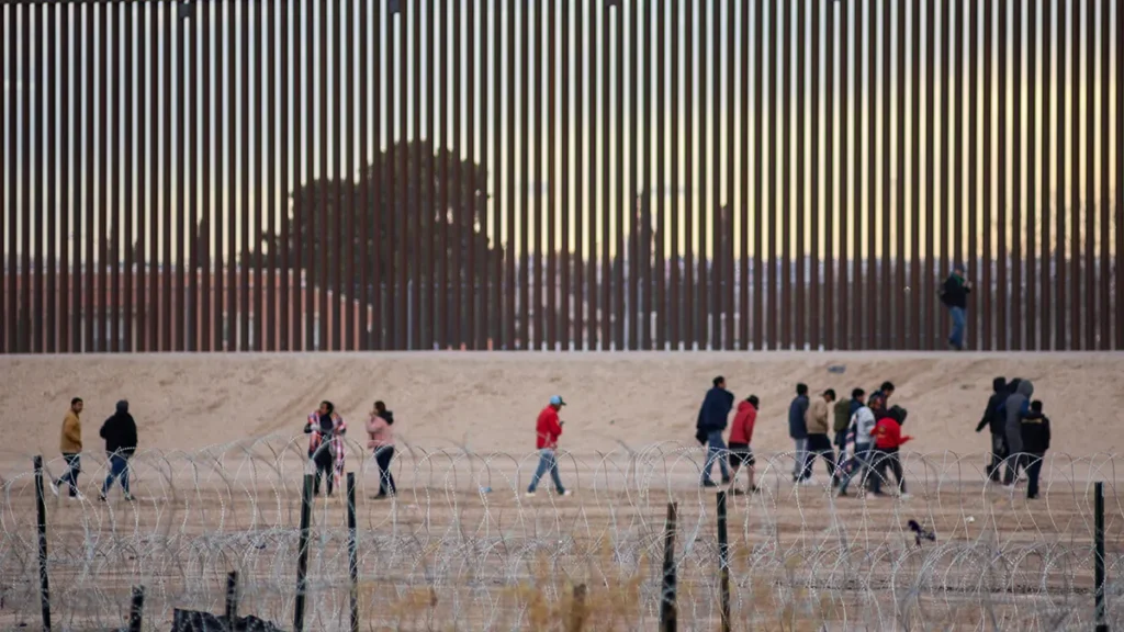 Self-deportation under Trump is working: People walking along the border barrier at sunset